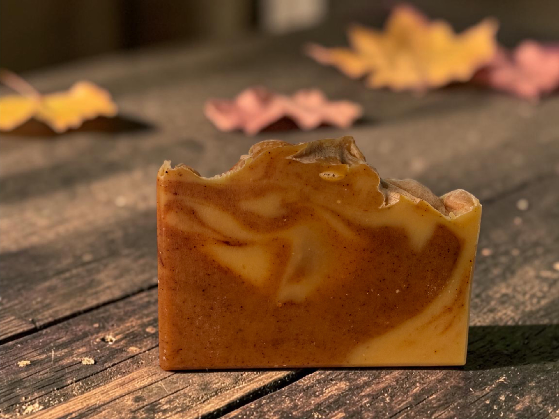 Turmeric Pumpkin Soap, a handcrafted bar swirled in warm golden and amber tones on a wooden surface